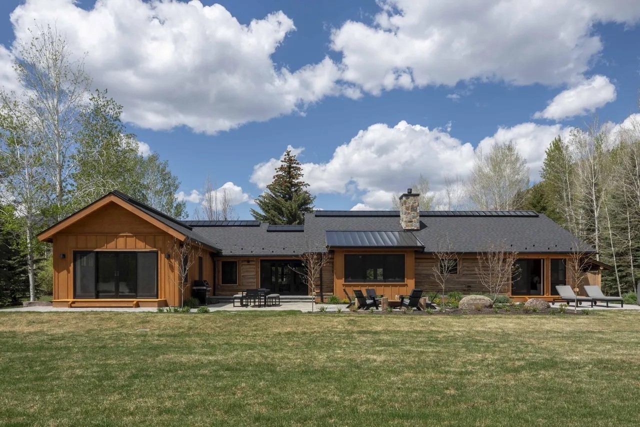 Single-story modern home with a metal roof and a wide lawn under a blue sky