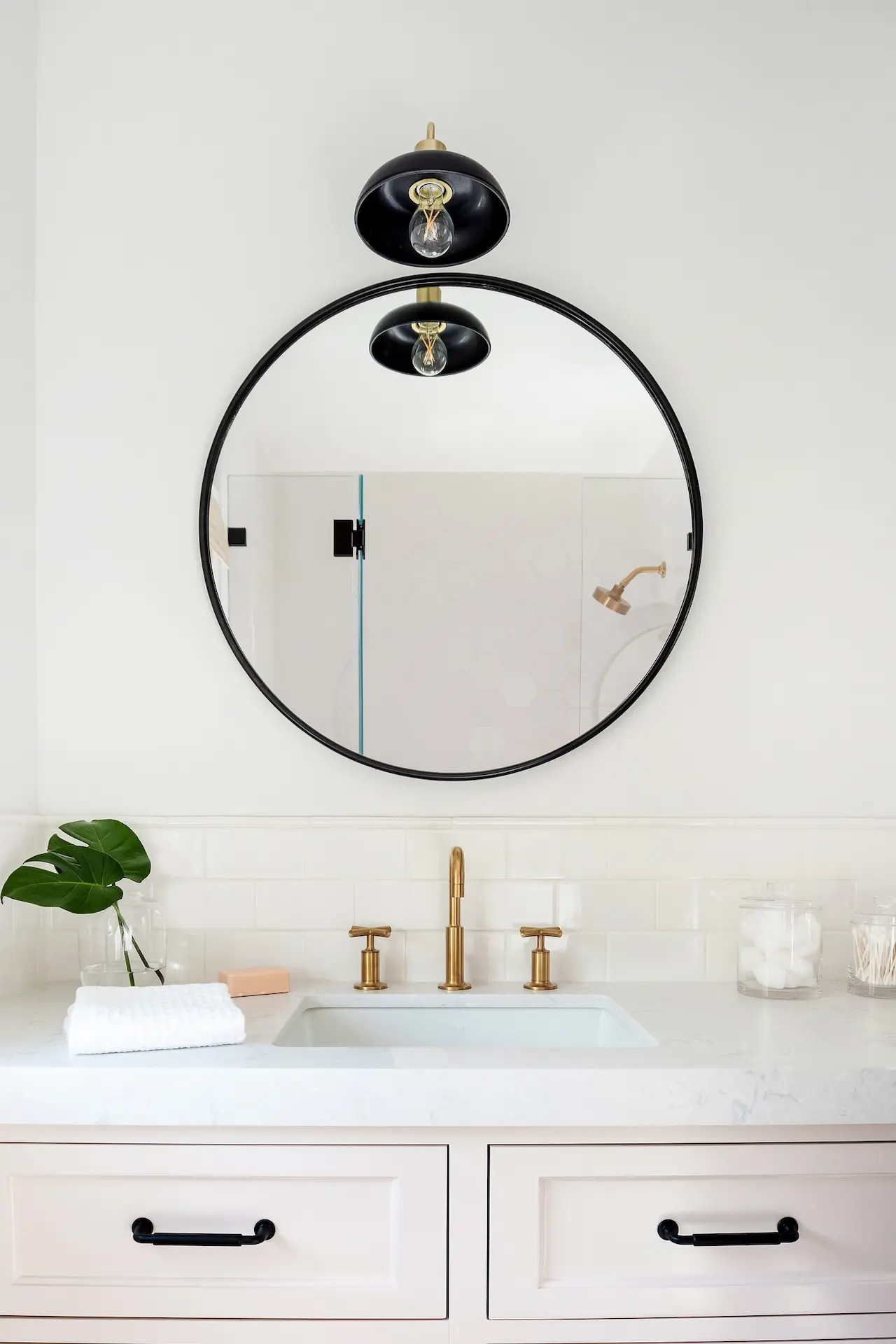 Elegant bathroom with a blush vanity, brass fixtures, and a round mirror in the North Tustin Remodel & Addition. Photo by Molly Rose.