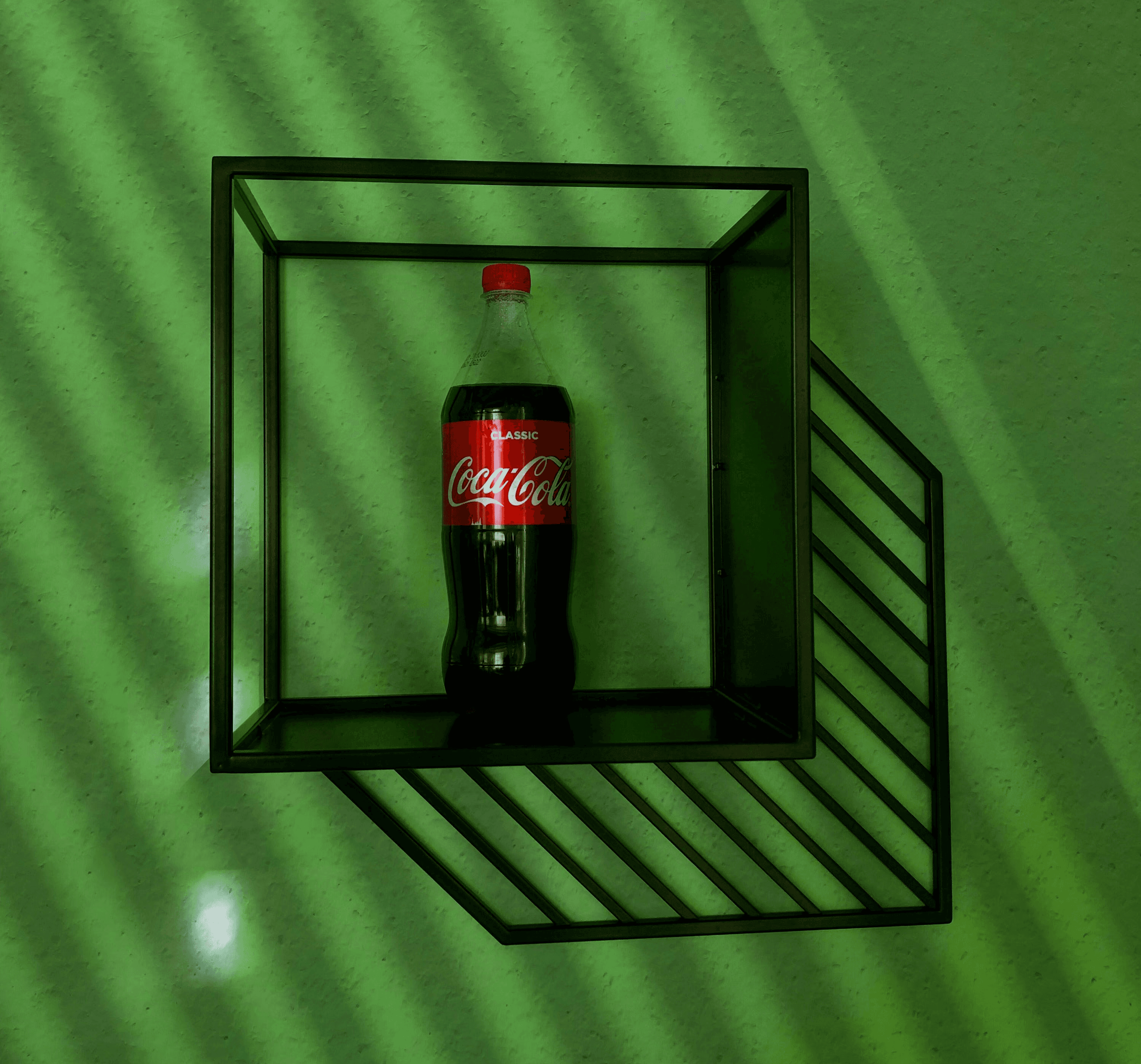 a coca - cola bottle in a shadow box on a green wall