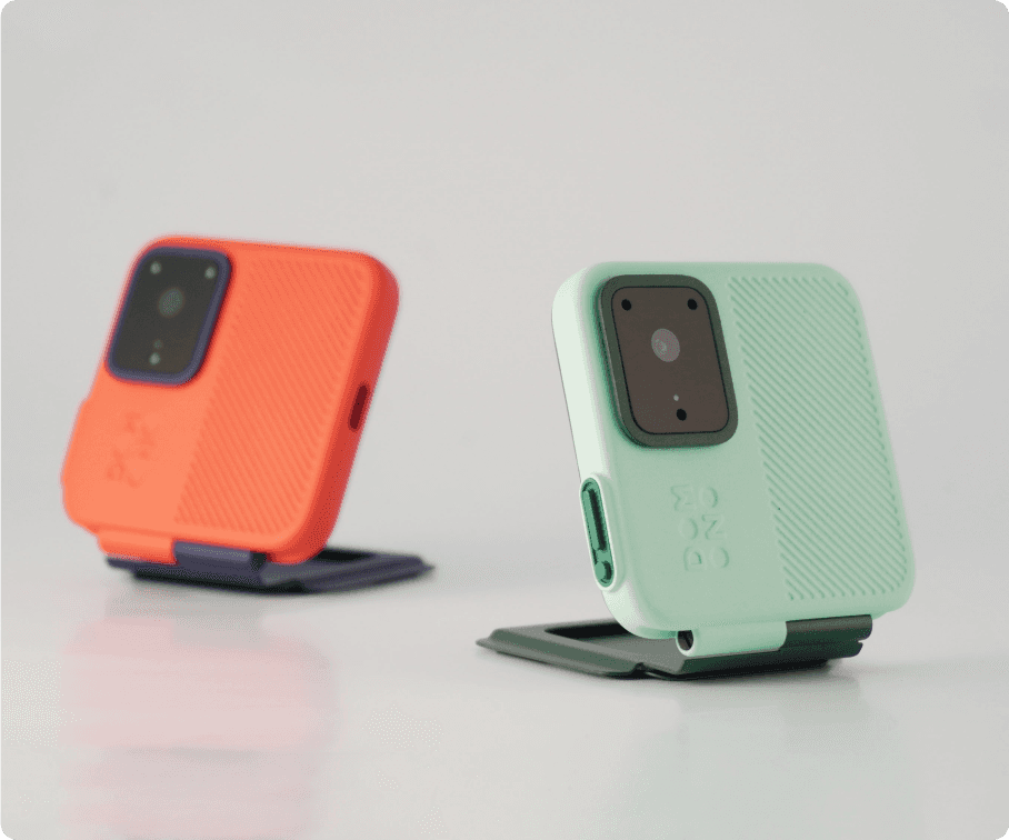 Two different colorways of a portable action camera, showcasing the sleek design in contrasting shades, ideal for attaching to a smartphone case.