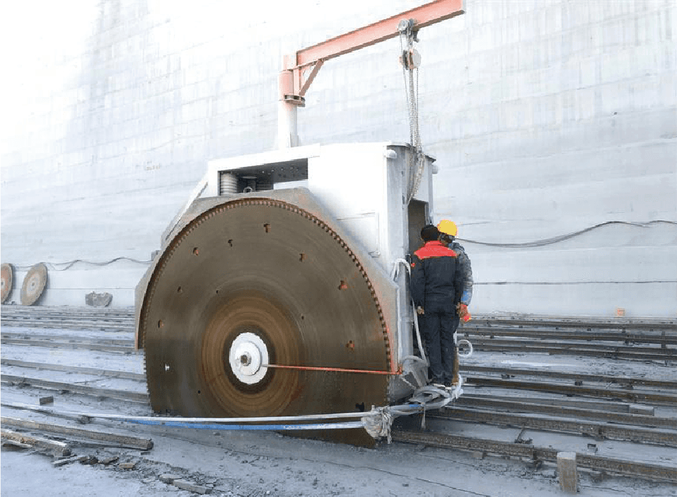 Two workers operating a Double Blade Cutter Stone Quarrying Machine in a quarry setting, showcasing the machine's large blades and sturdy build designed for cutting large stone blocks.