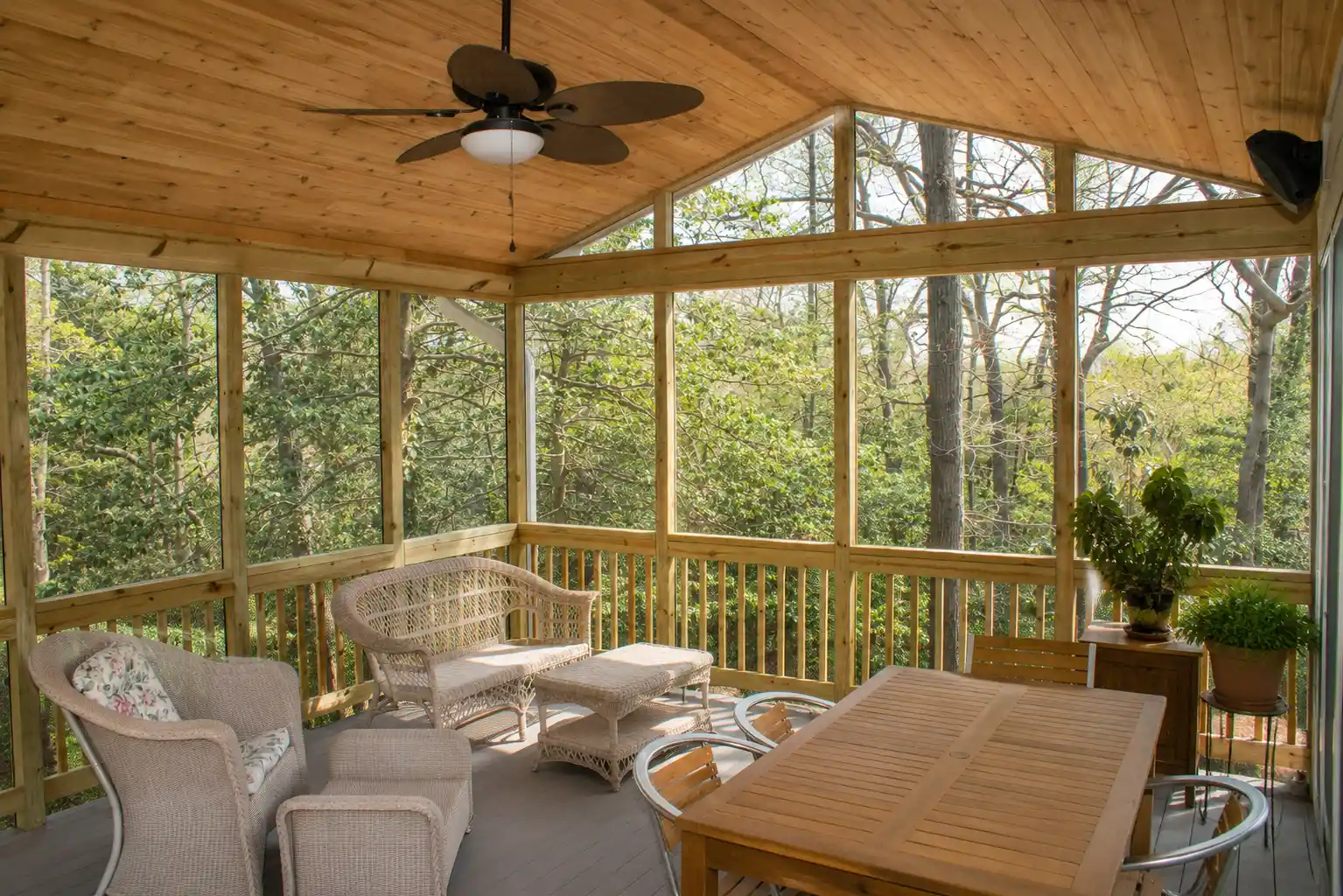 Custom screened porch addition with natural wood ceiling, ceiling fan, and comfortable outdoor living area