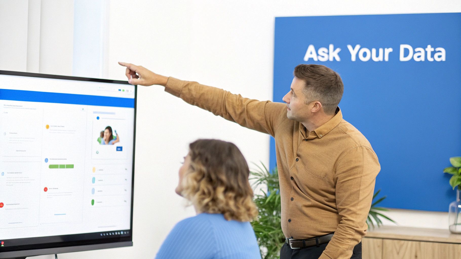 Two business professionals analyzing data on a large screen in an office with an 'Ask Your Data' sign.