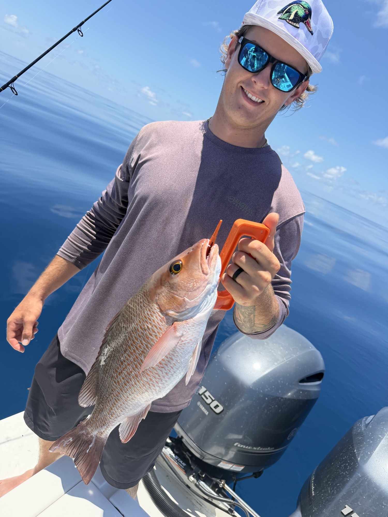 Angler holding a mangrove snapper on the deck of the Nautical Native