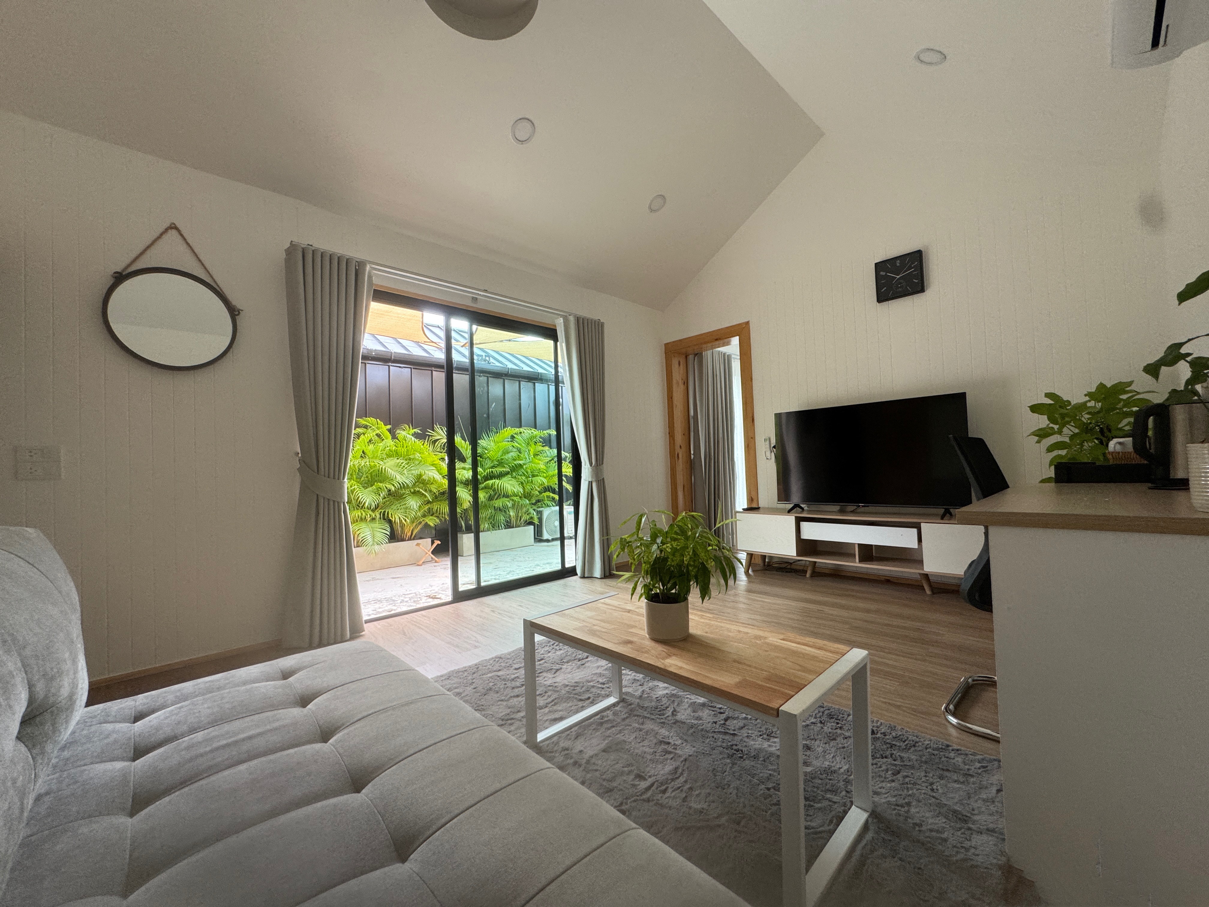 A bright sitting area with a smart TV and large sliding doors that let you enjoy the tropical greenery right from the sofa.