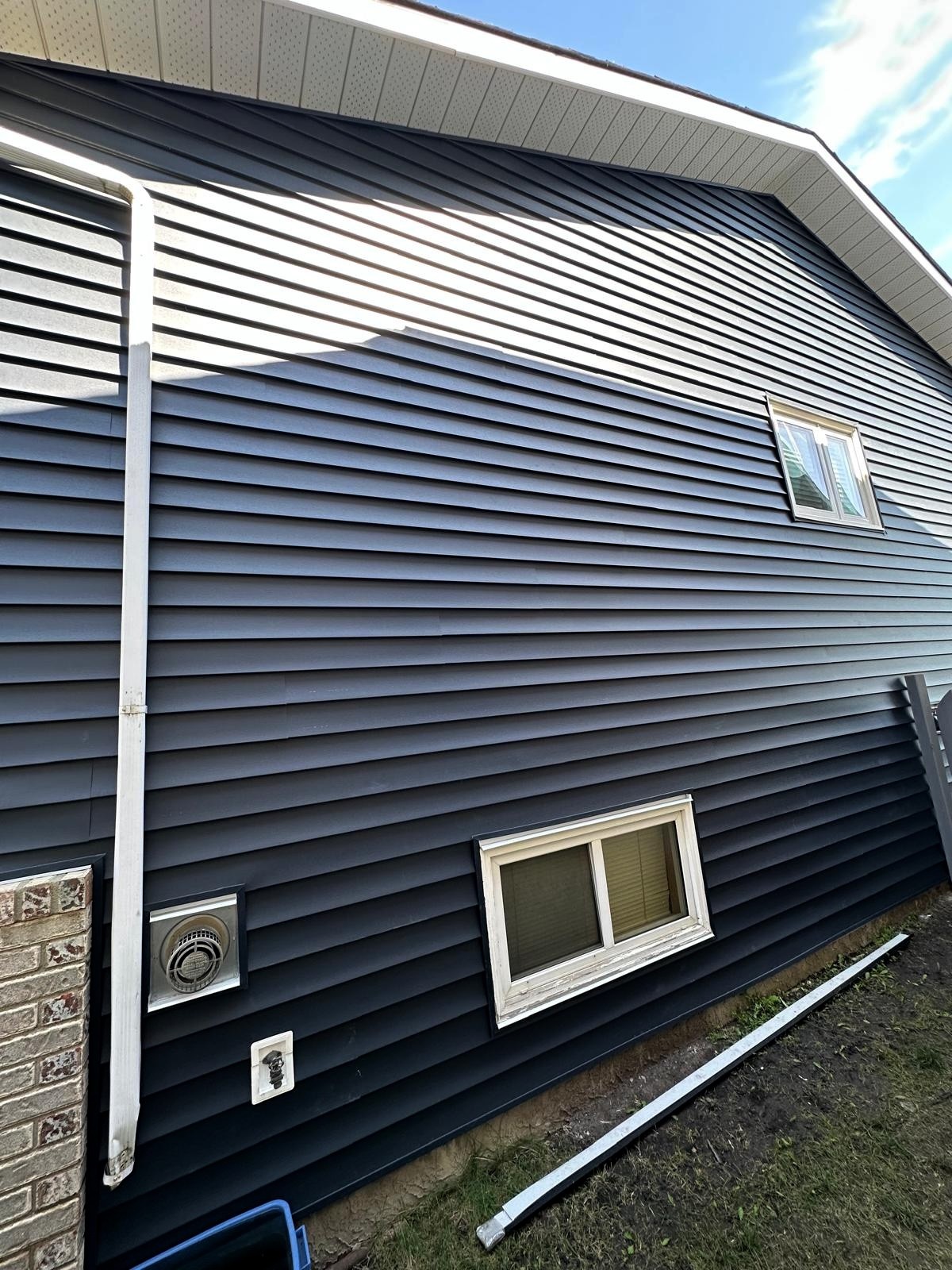 Deep-blue vinyl re-siding with vented soffit & fascia—tight lines, low maintenance, Calgary-ready.