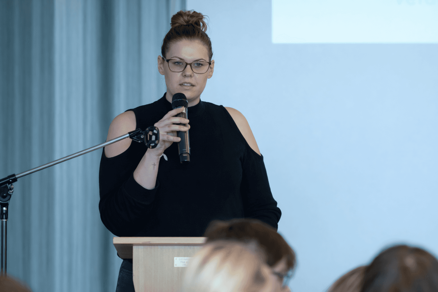 Green microscopic organism with textured surface and smaller structures surrounding it on a black background.