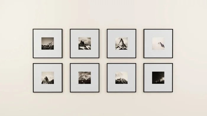 Eight framed mountain photographs arranged in two neat rows on a wall.