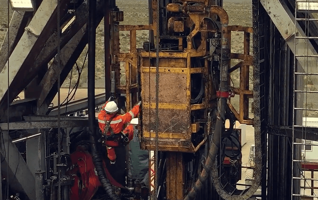 A photo of a frontline worker, at height, working on an a land based oil/gas production platform