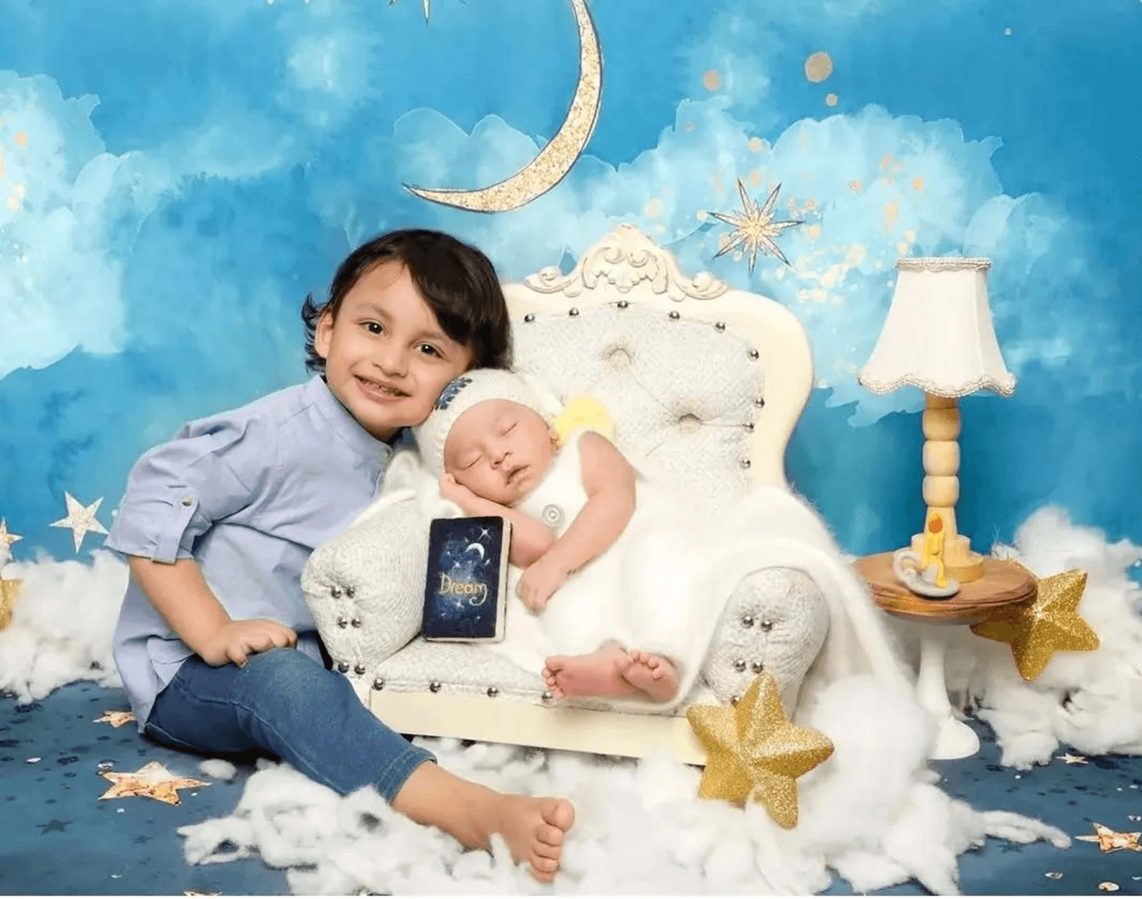 An older brother is sitting next to a sleeping newborn.