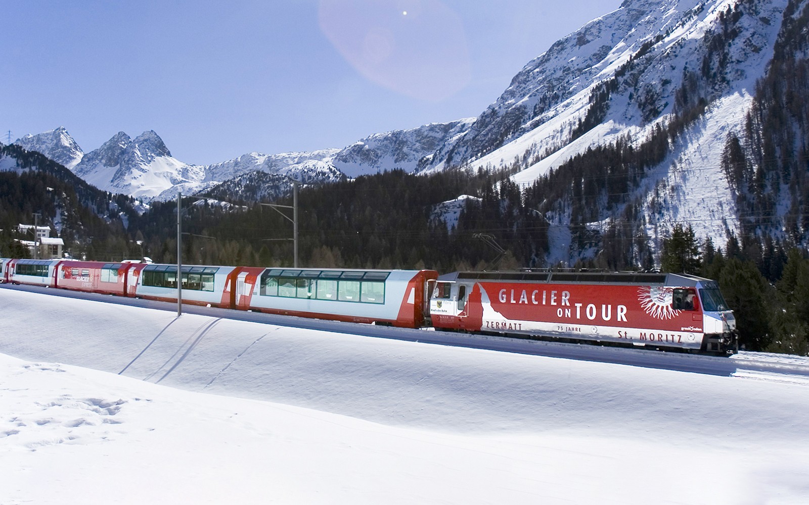 Glacier Express train traveling through snowy mountains near St. Moritz.