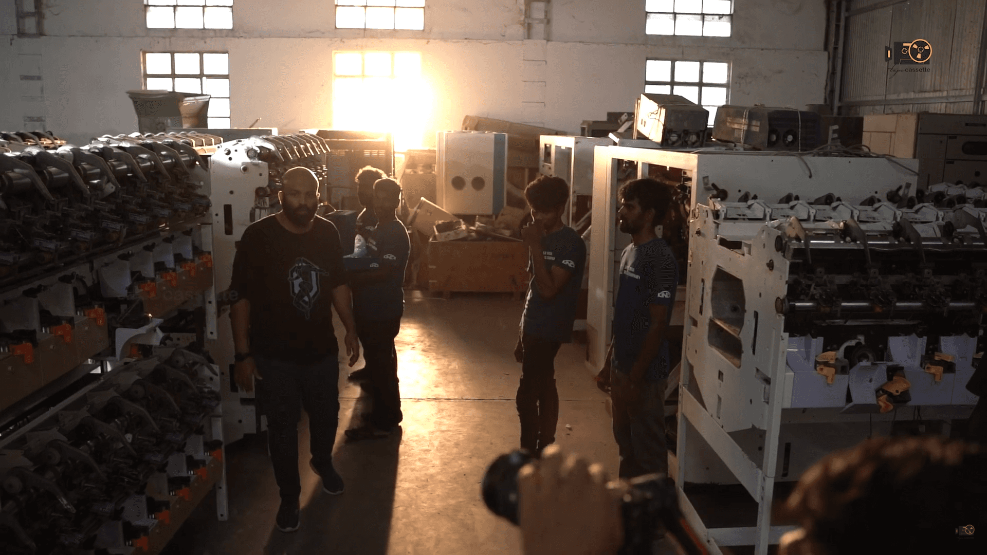 Behind the scenes of industrial corporate film shoot, crew setting up gear in a factory location