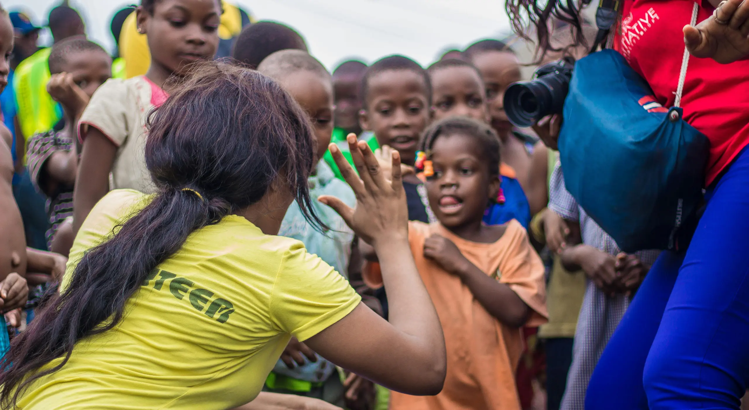 Volunteer high-fiving children outdoors.