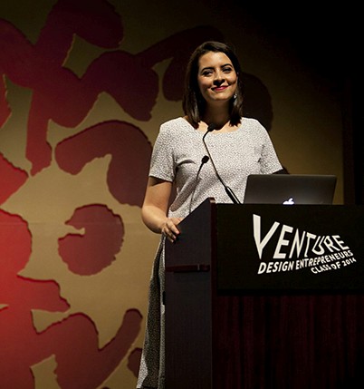 a woman in a grey dress is giving a speech