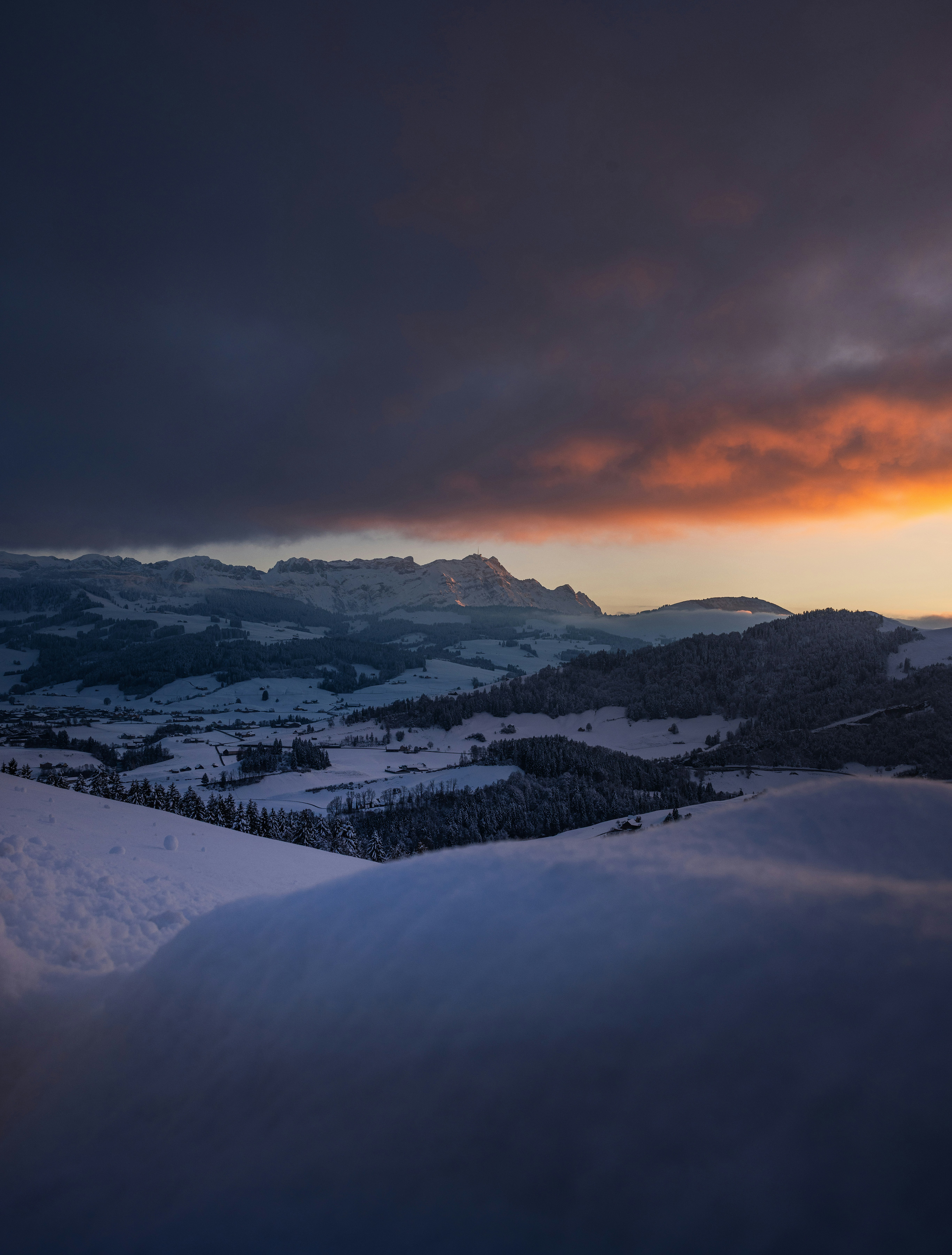 Snowy mountain landscape at sunset with dramatic clouds
