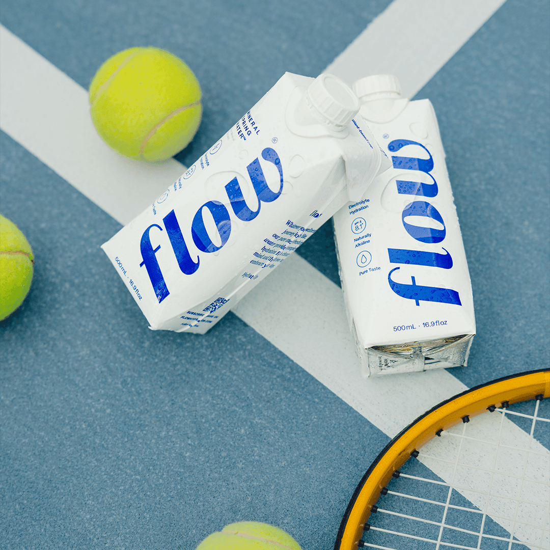 Editorial portrait of a bald model with a white clay mask on face and body, neutral backdrop.