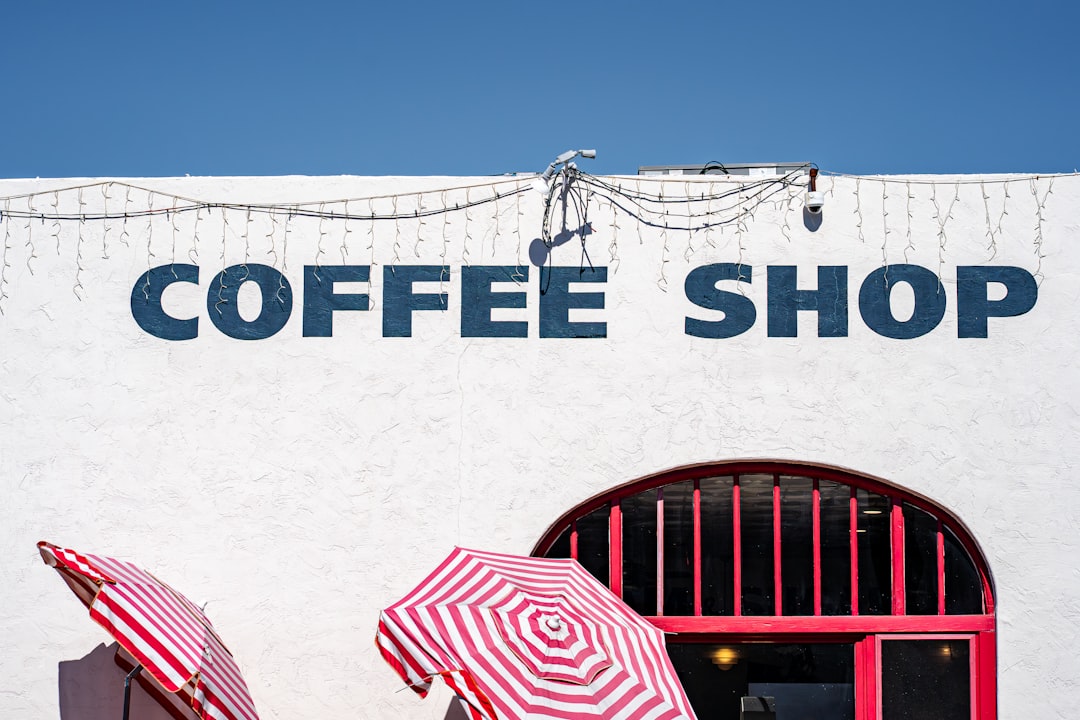 White building with "coffee shop" sign and umbrellas