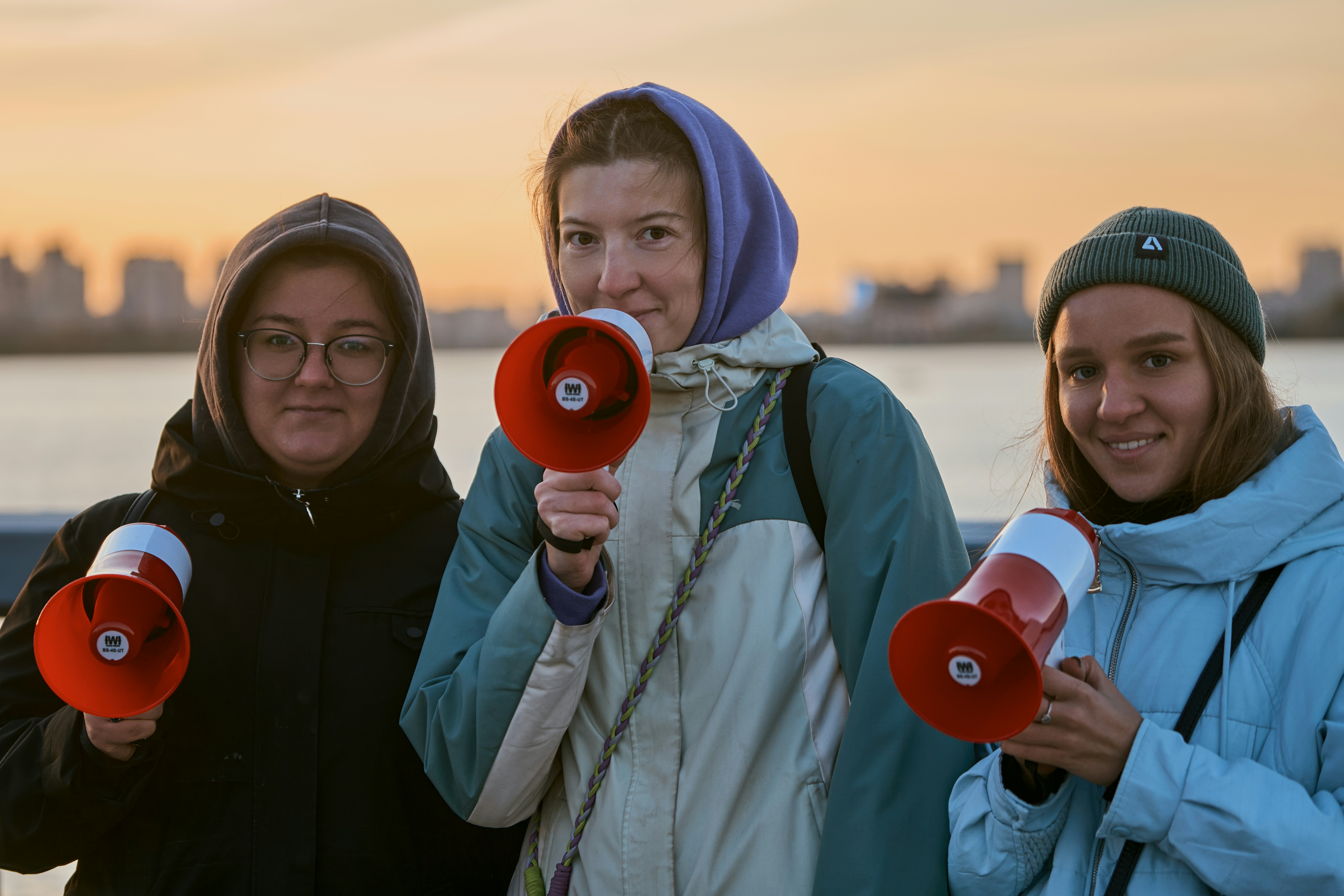 Three women holding megaphones at sunset