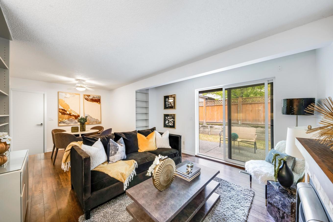 Modern living room with a dining area, large windows, and wooden flooring creating a bright, open atmosphere.