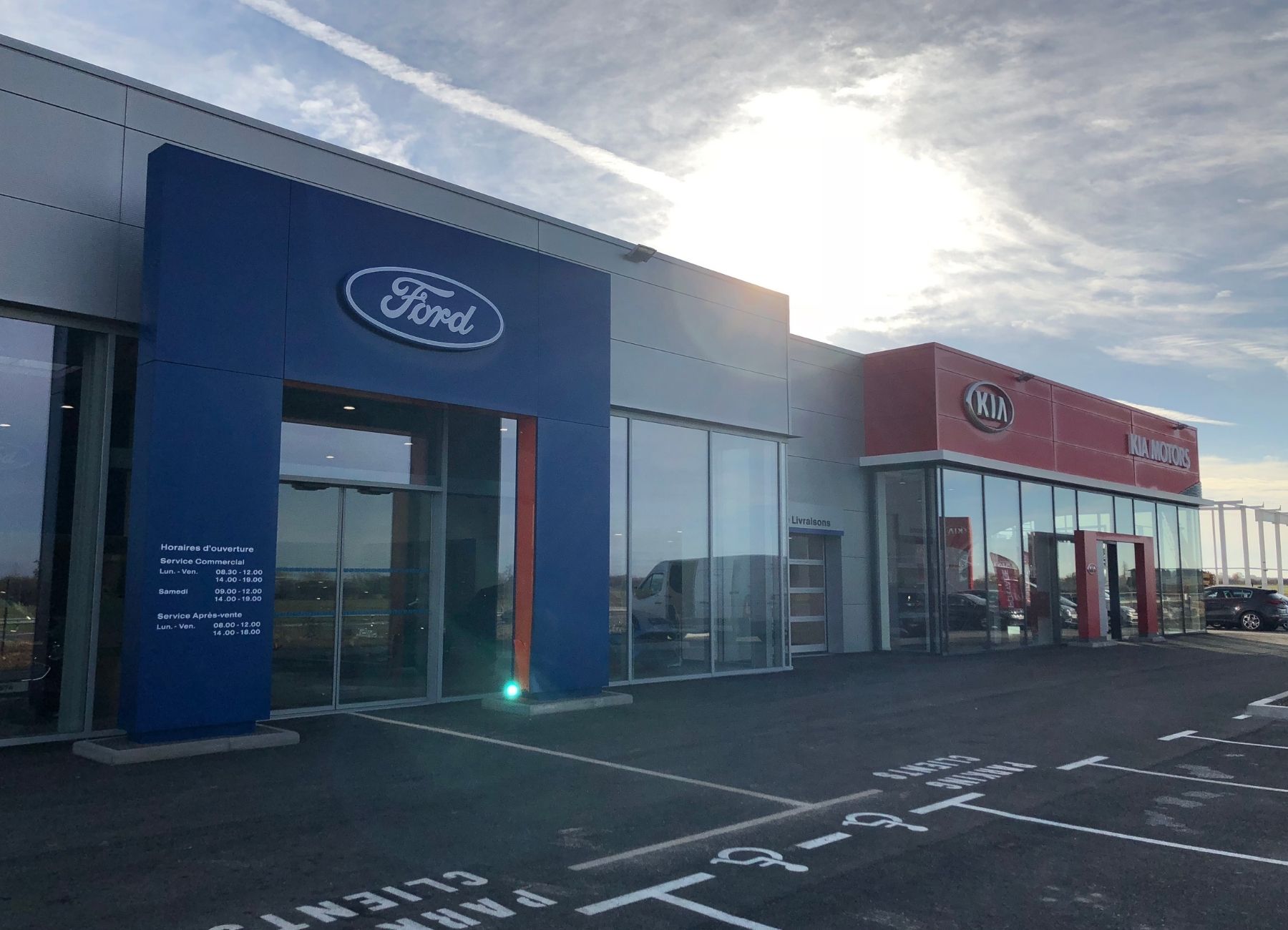 Vue extérieure d’un bâtiment commercial avec bardage métallique bleu et enseigne lumineuse.