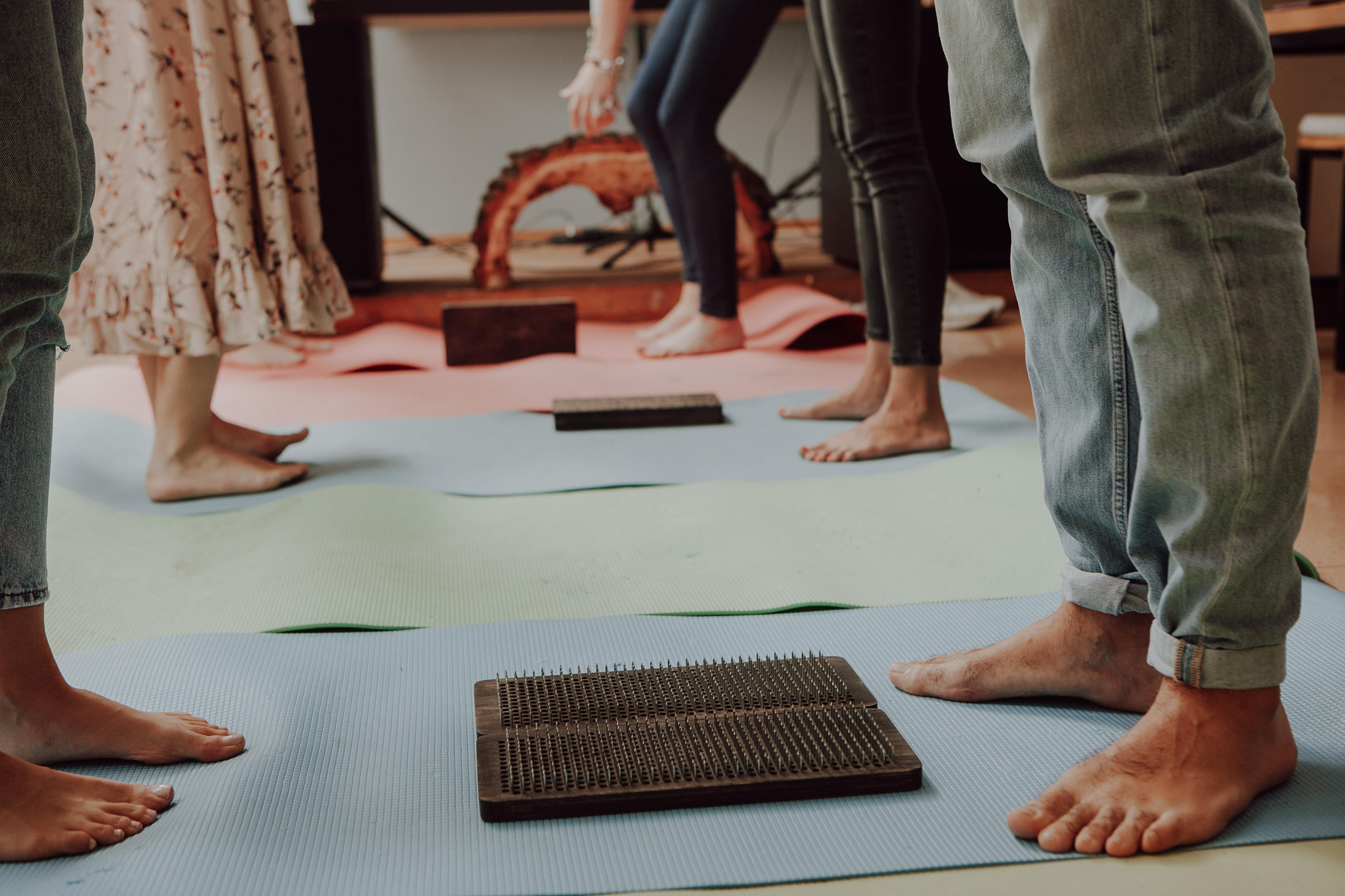 A winding road cuts through rocky terrain, surrounded by patches of green grass and illuminated by sunlight.
