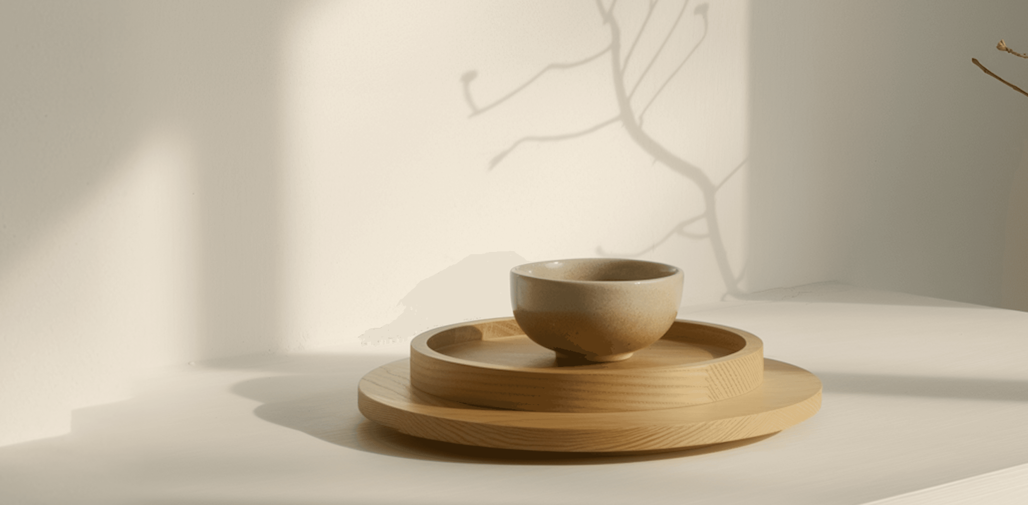 Two elegant vases, one amber glass with twigs, the other beige ceramic.