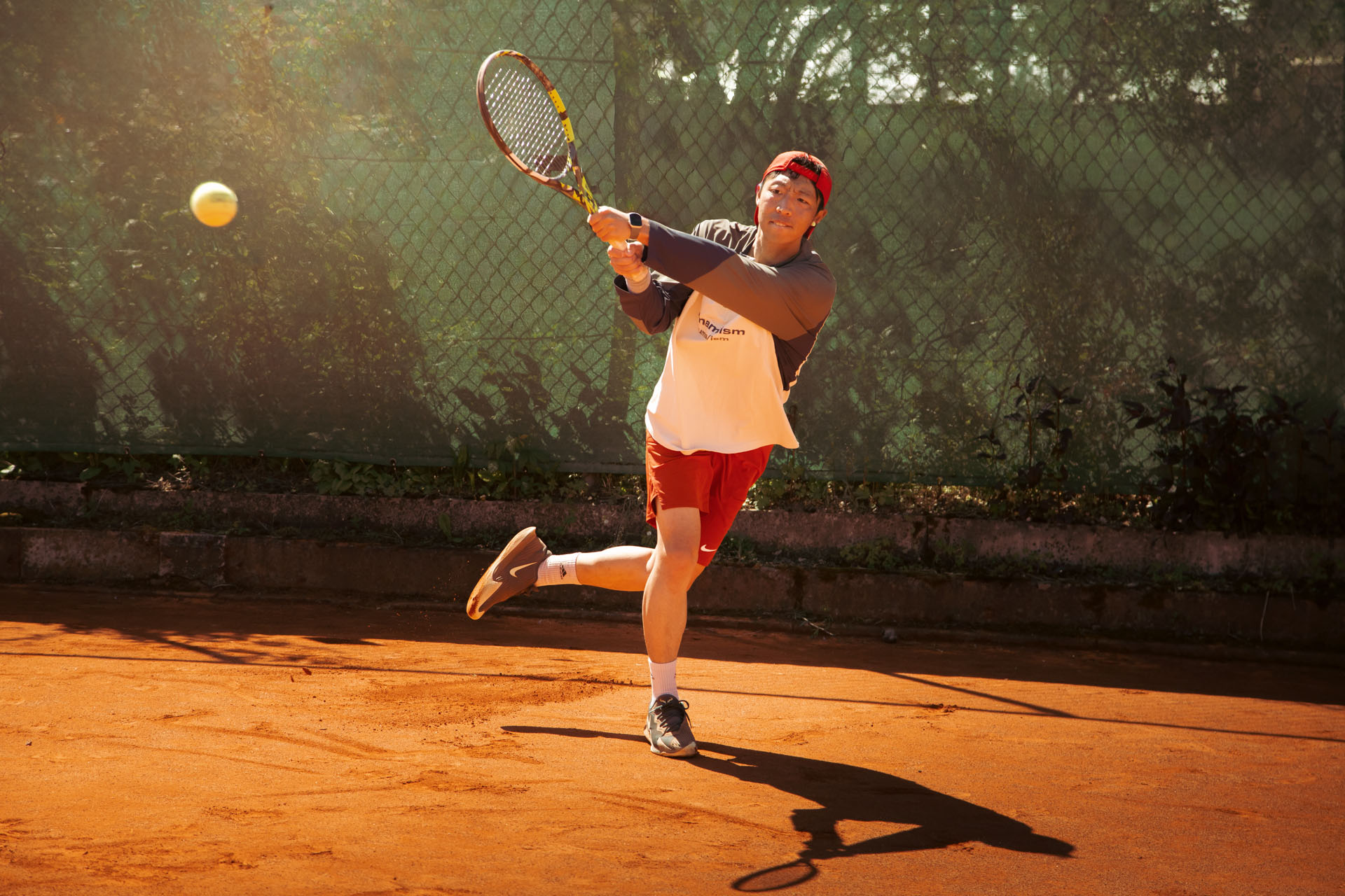 Tennismeisterei Hero Banner mit Tennisspieler der einen dynamischen Rückhandschlag macht.