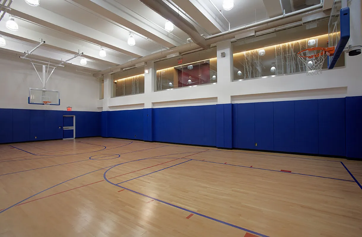 Indoor basketball court showcasing blue walls and a gleaming wooden floor, designed for sports activities.
