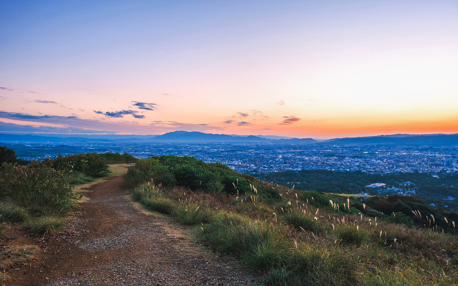 在日本奈良的一日游中,从若草山欣赏夕阳美景,眺望城市景观和远处的群山。