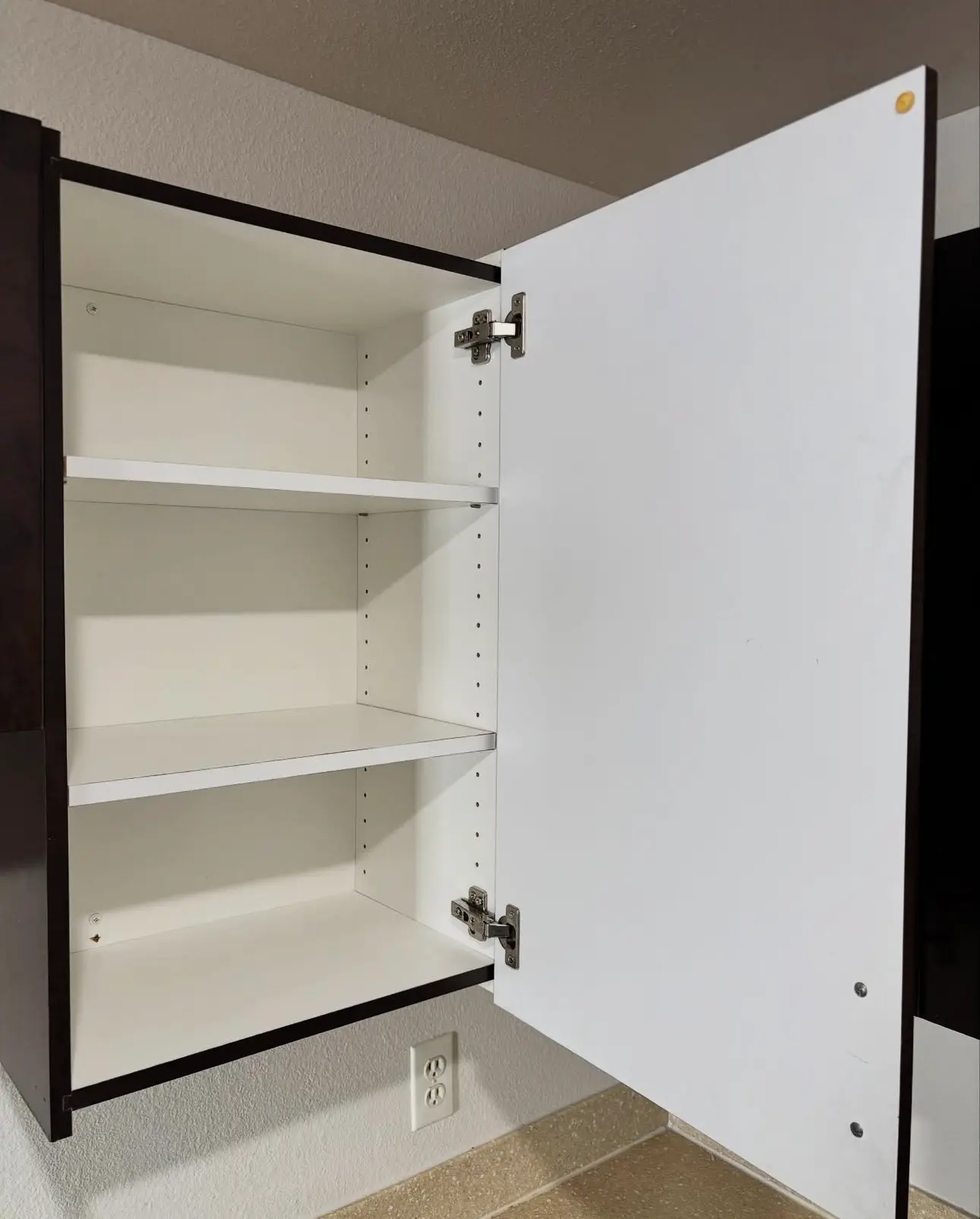 Interior of a deep cleaned kitchen cabinet with spotless white shelving and dust-free hinges.