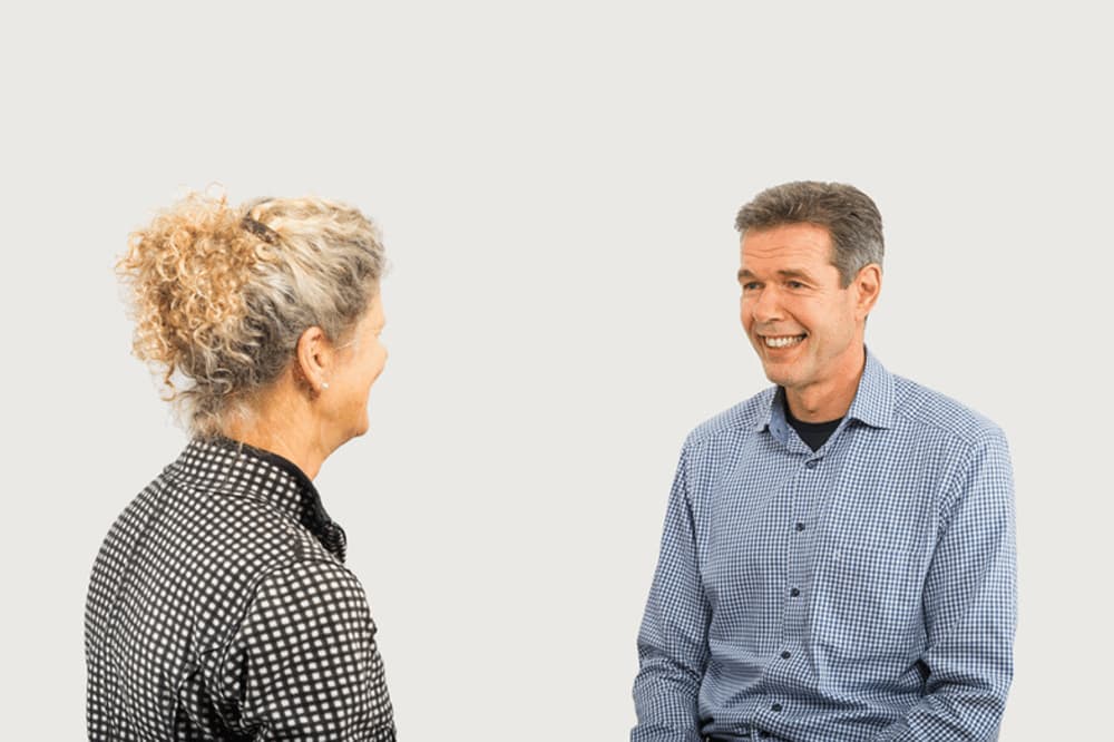 Zwei Personen im Gespräch, lächeln sich an. Dialog, Unterhaltung.