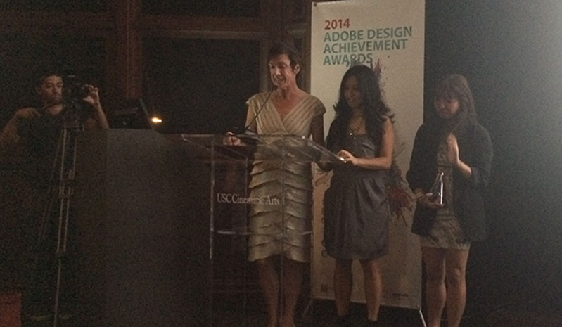 a woman speaking on the mic and she has two other women next to her