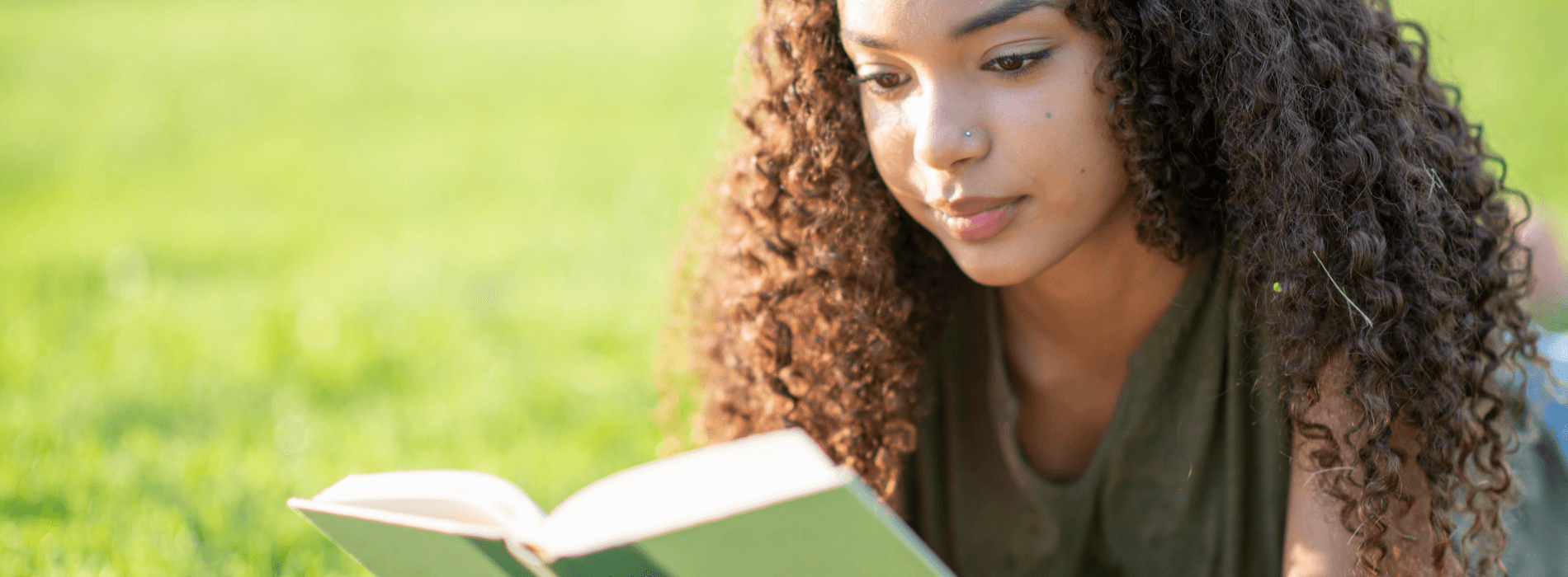 Femme qui lit un livre dans un parc allongée sur l'herbe