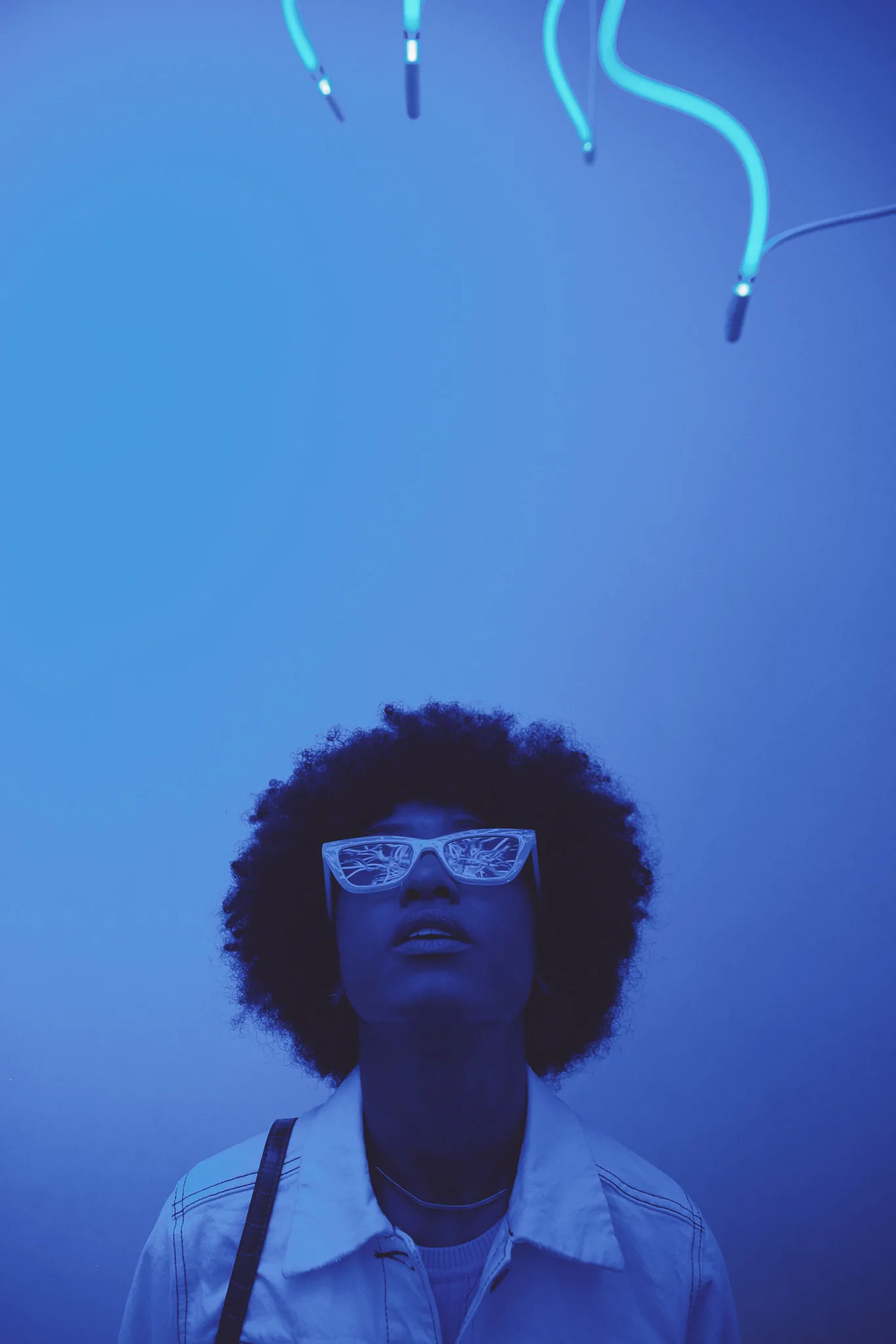 woman tilts head back under neon tubes — lifestyle photography by Tom Kubik