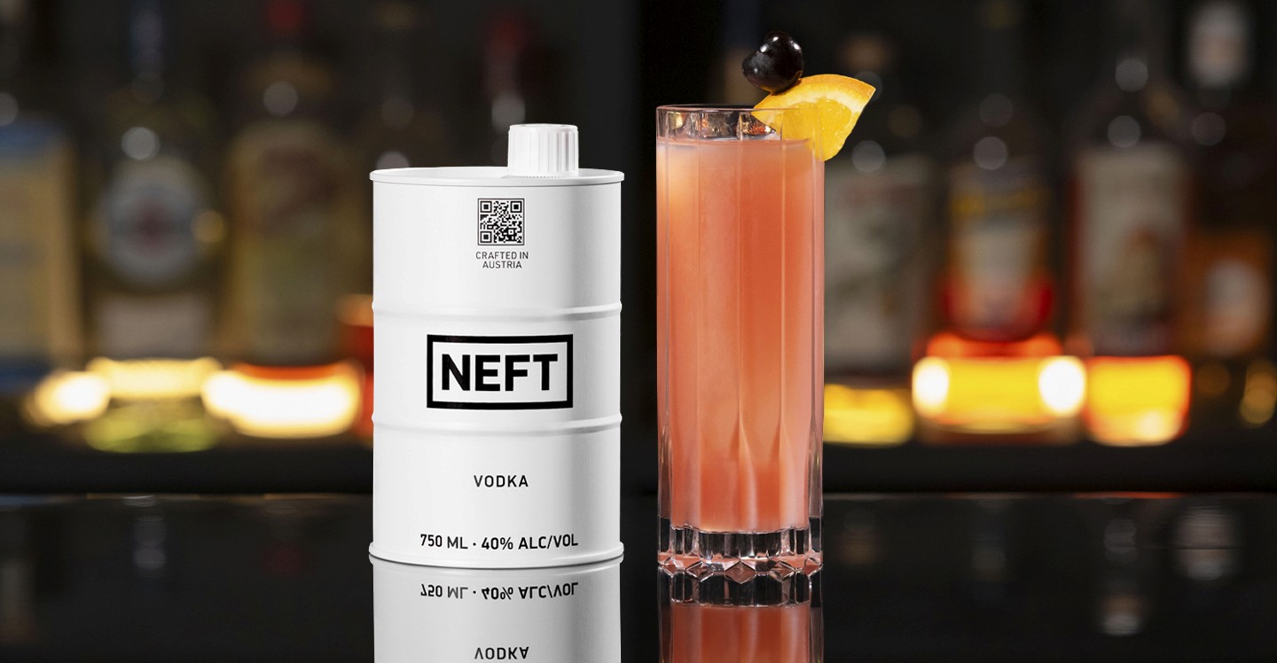 A NEFT Barrel and a glass of Sex on the Beach on a bar counter.