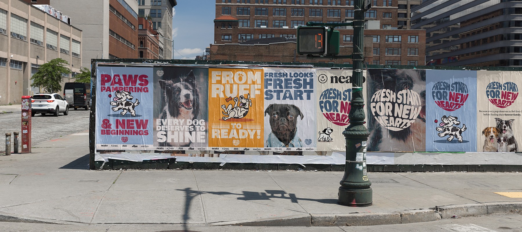 A row of colorful dog-themed posters on a city construction wall featuring slogans like “Paws Pampering” and illustrated dogs in playful poses.