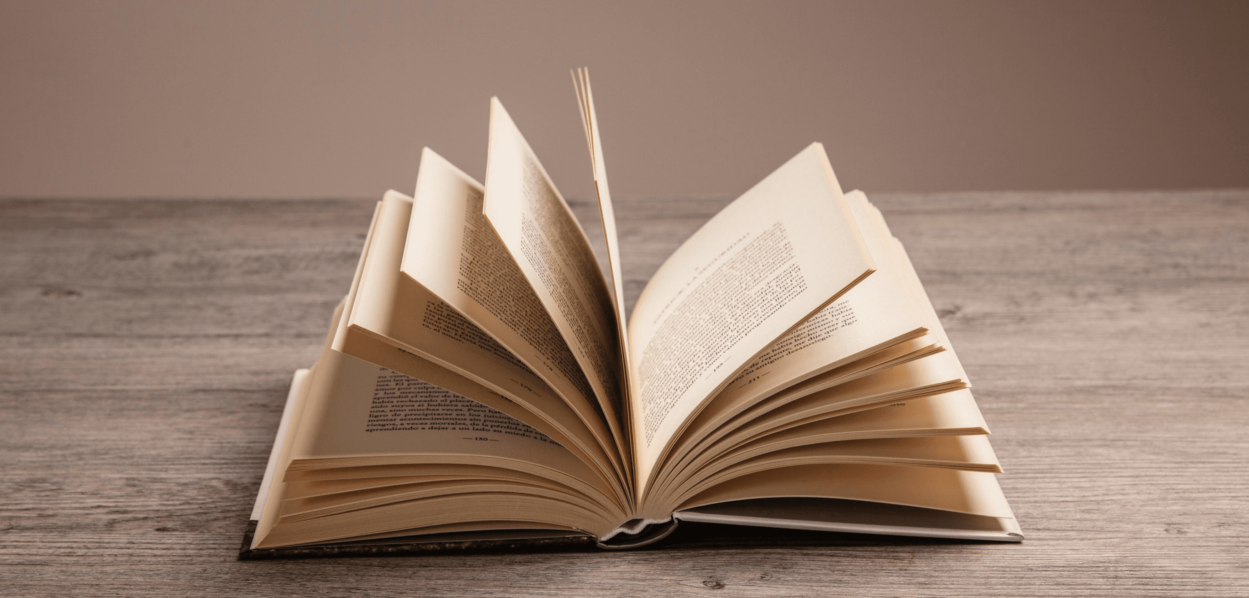 Open book with fanned-out pages on a wooden table.