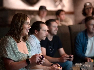 4 people with video game controllers in their hands playing a game off screen