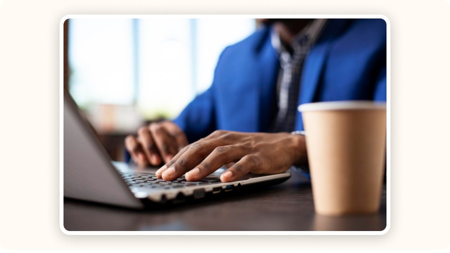Personne tapant sur un ordinateur portable avec une tasse de café sur le bureau