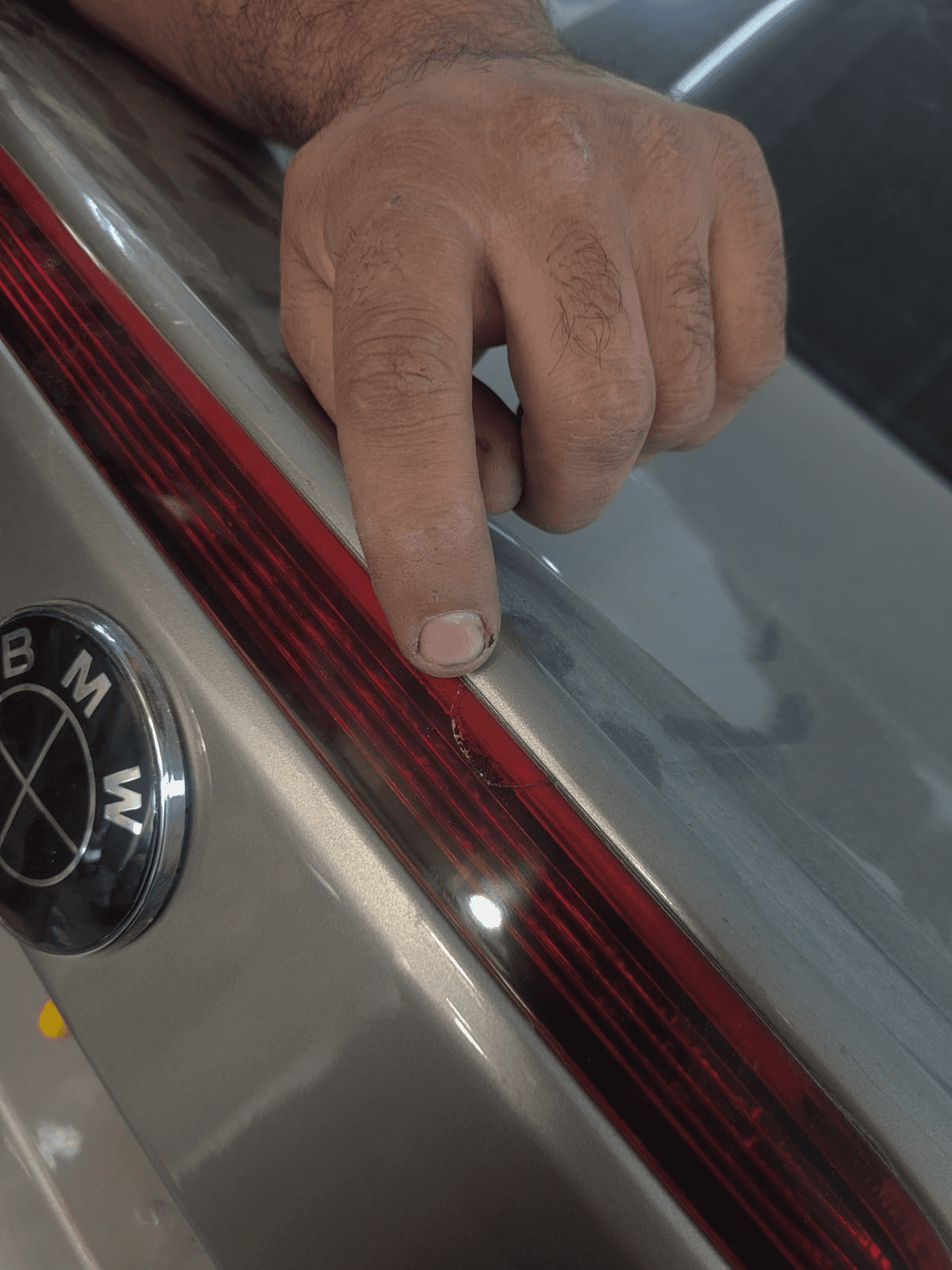 Technician inspecting a scratch beside a BMW rear tail light in Mussafah, Abu Dhabi