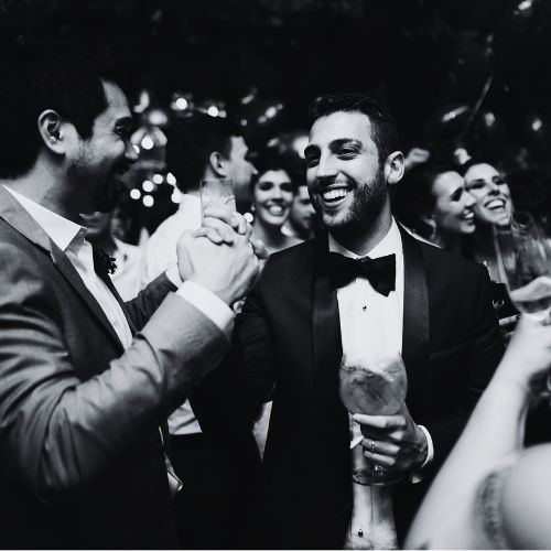 A group of guests dancing and laughing at a wedding reception, the dance floor alive with movement, while colorful lights enhance the celebratory mood.