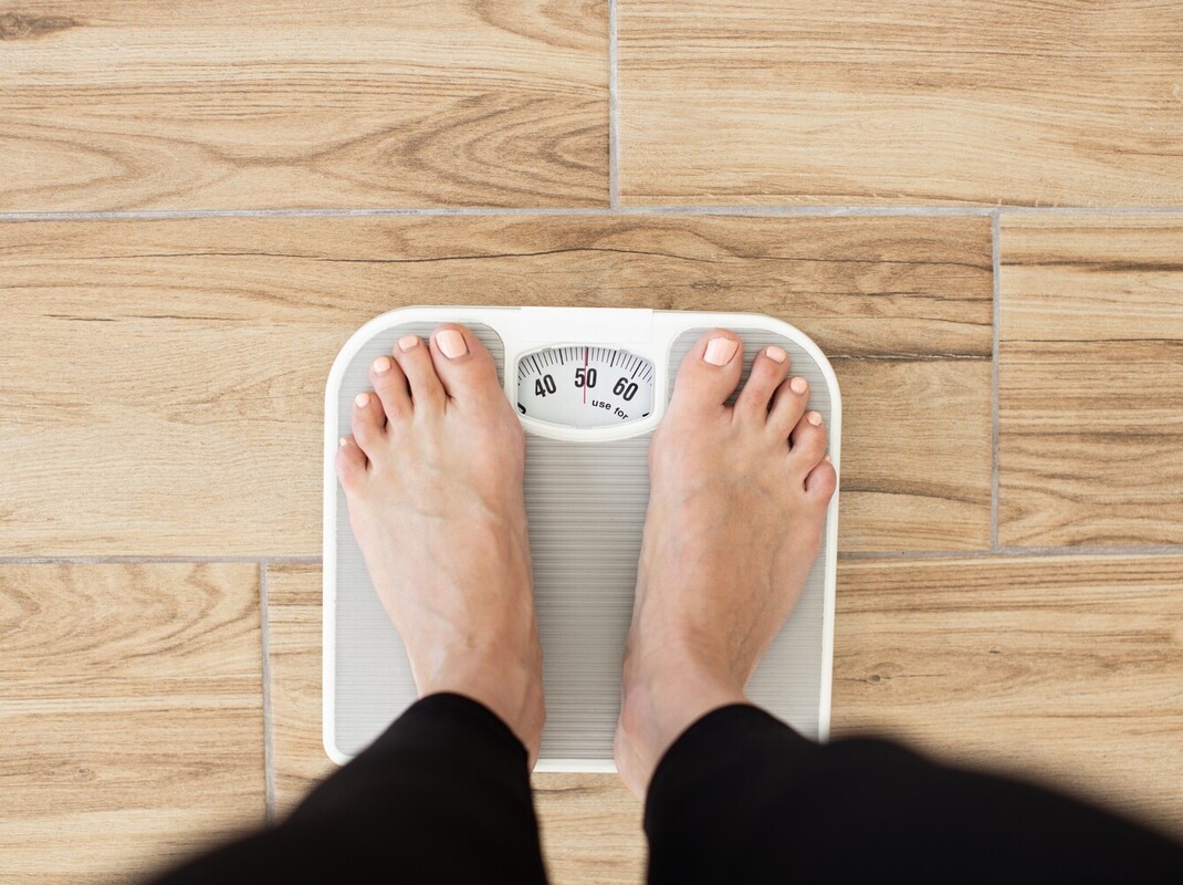 woman using a scale to check her results from her weight loss sauna routine
