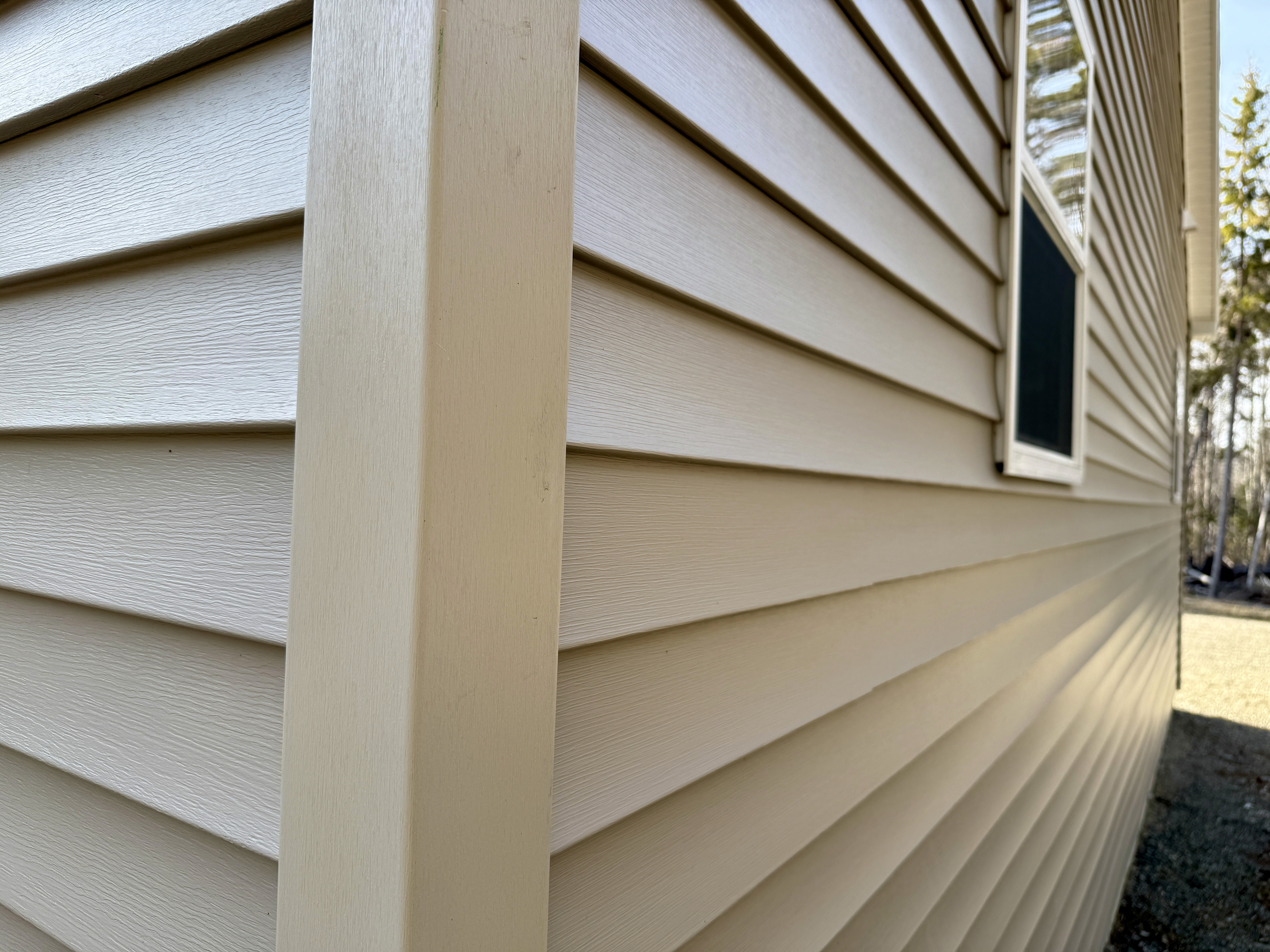A bluish gray home with white trim, with brand new hardie board siding installed by Wells Built Roofing