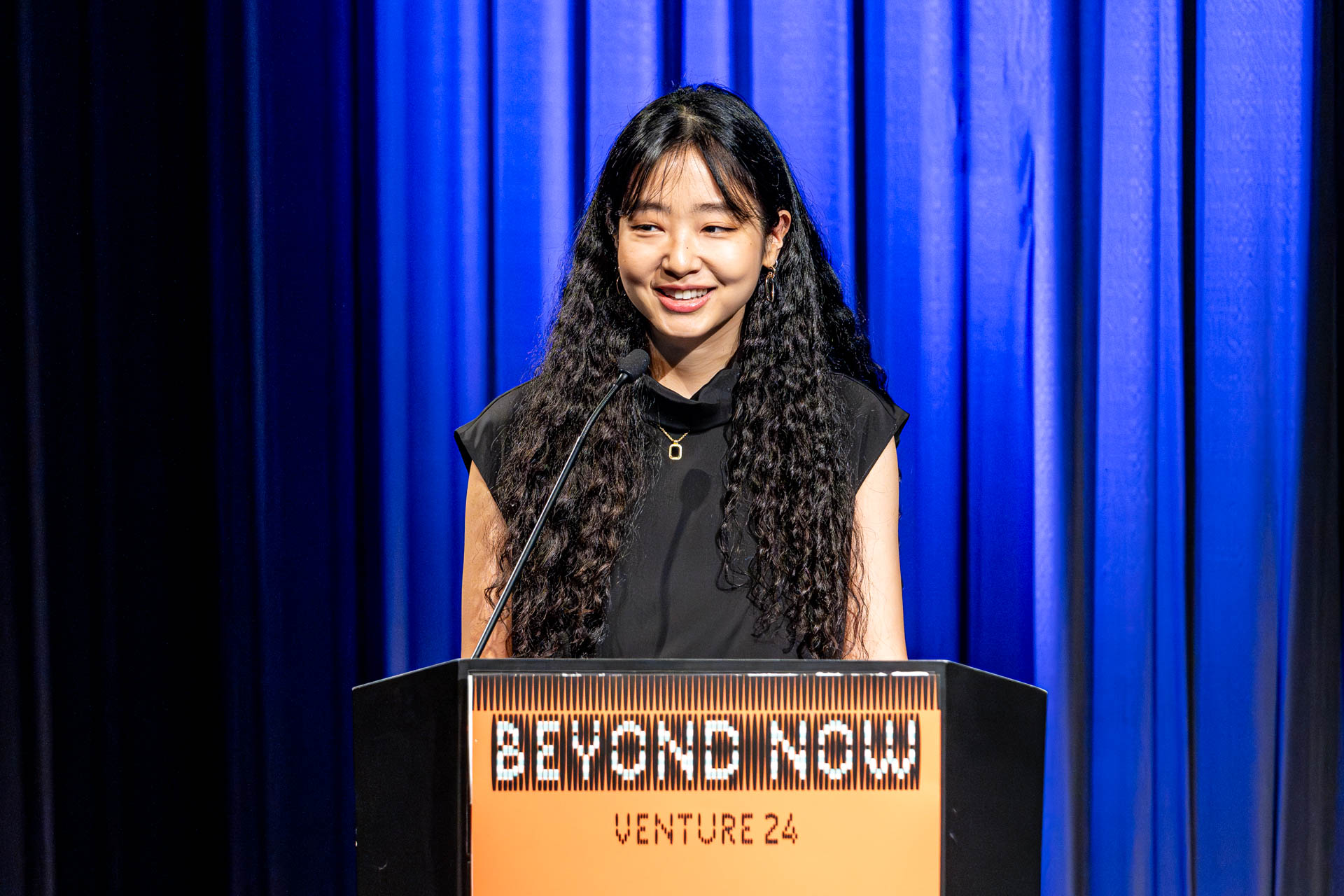 a student at a podium presenting a project in a Theatre