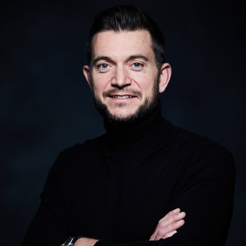 man in gray suit jacket smiling