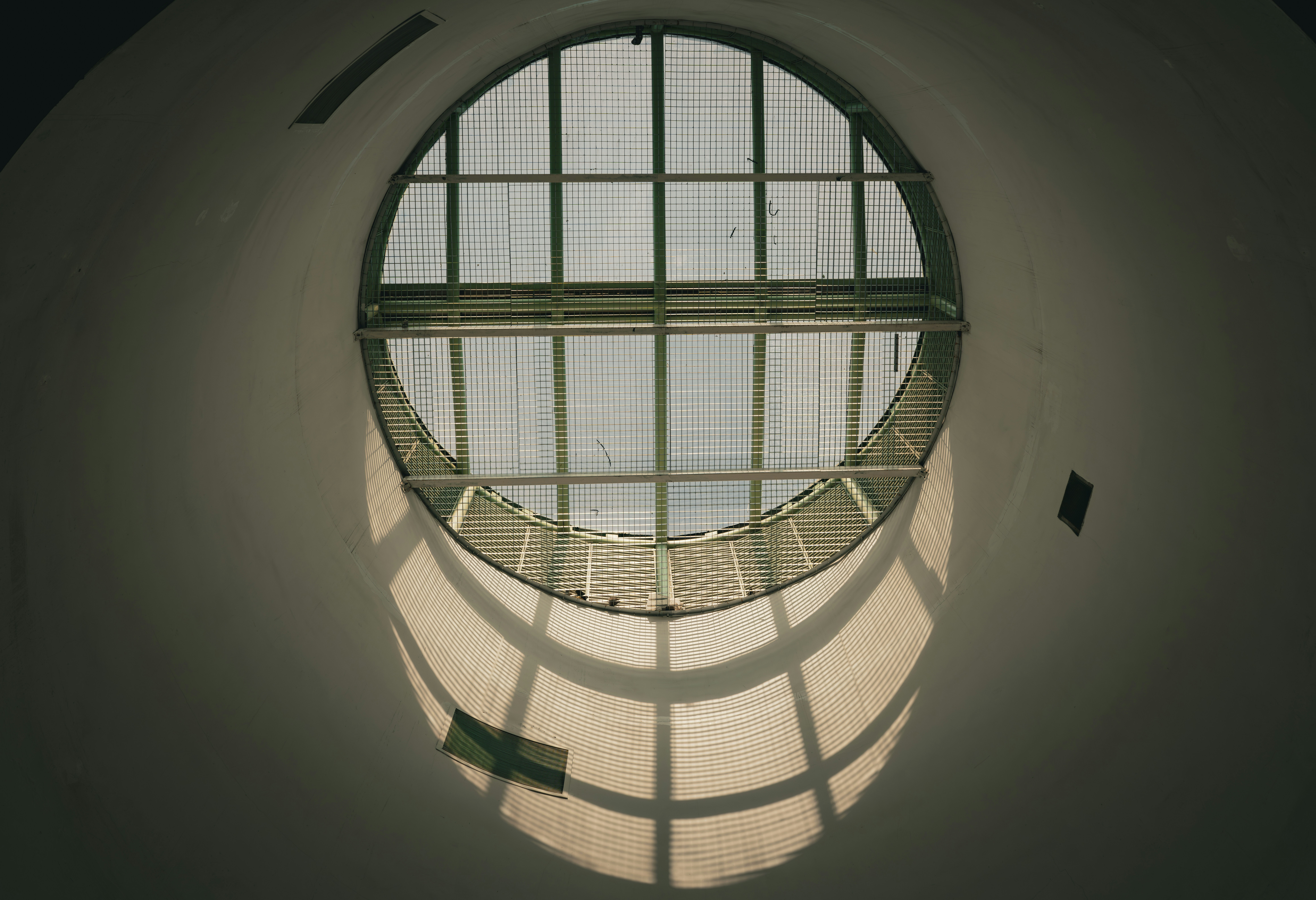 Round window with sunlight casting a grid shadow