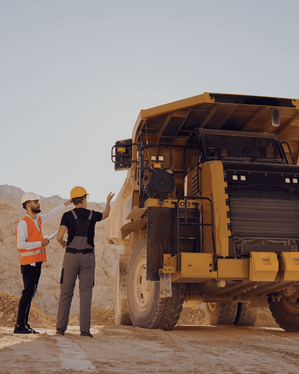 Two engineers standing beside a truck at a mining site.