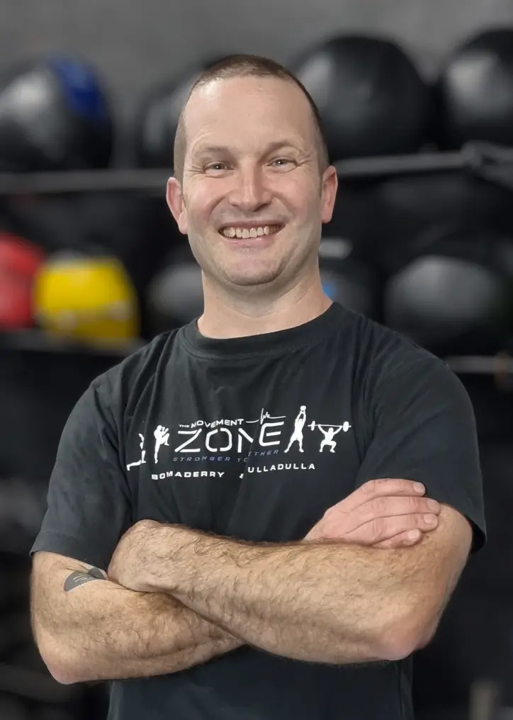 Coach Anto Newton posing in The Movement Zone shirt inside the training facility.