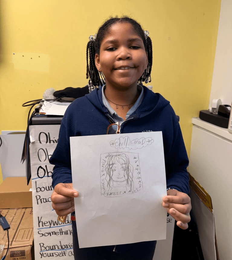 A young student shows off her self-portrait