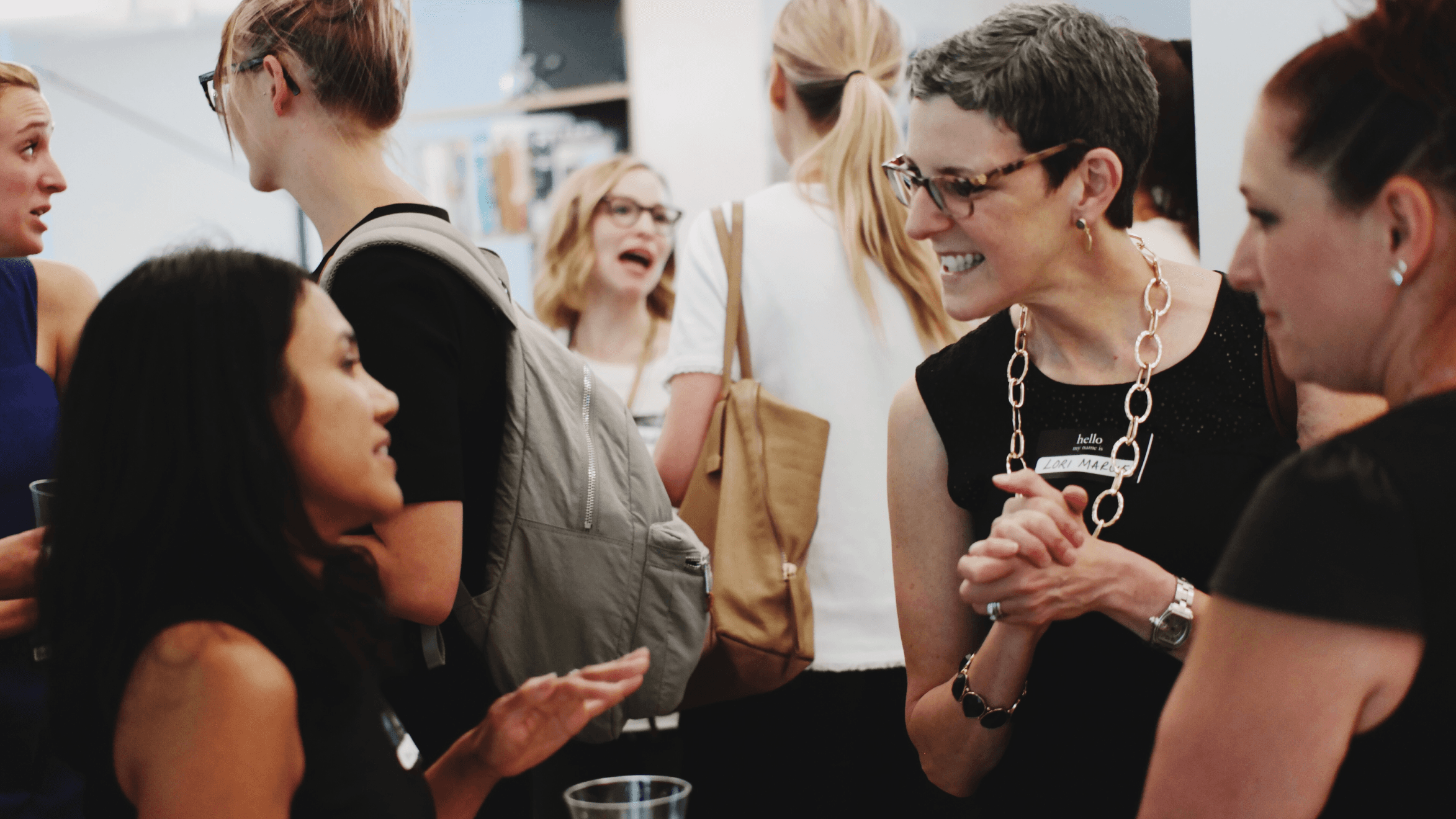 Four women socializing at an event, dressed in vibrant outfits, engaged in conversation and enjoying each other's company.